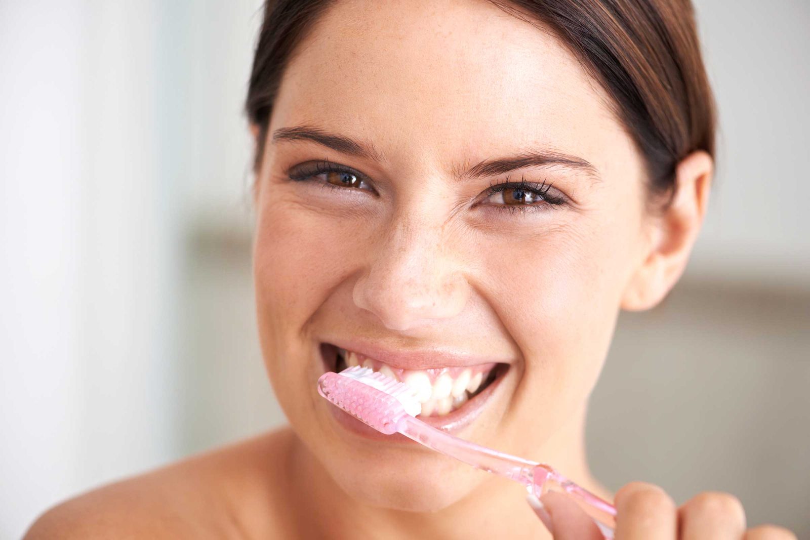 Smiling woman brushing her teeth